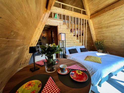 Cozy A-Frame glamping bedroom in Sasso di Castalda with wood beams, queen bed, mountain views, and dining area