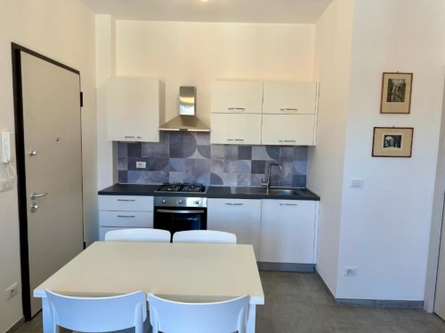 Cucina e zona pranzo moderna nell'appartamento Grecale di Welcome Holiday, Finale Ligure, con armadi bianchi e blu