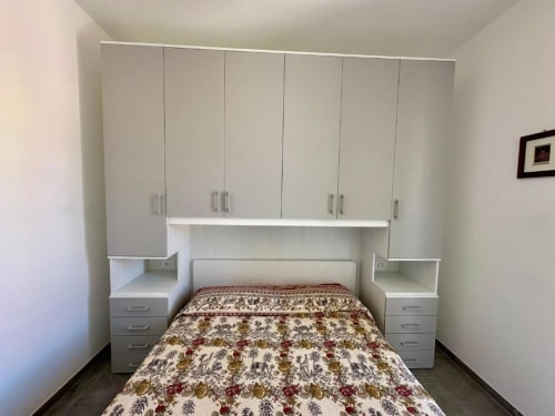 Camera da letto moderna con guardaroba incassato bianco e soluzioni di stoccaggio nell'appartamento Welcome Holiday Grecale a Finale Ligure