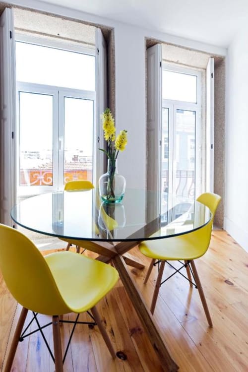 Sala de jantar de apartamento moderno com mesa redonda de vidro, cadeiras amarelas, pisos de madeira e janelas panorâmicas
