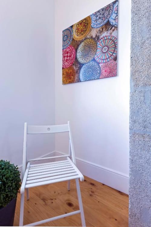 Cadeira branca sob tela de mandala colorida no apartamento Bom Porto, Porto