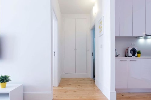 Corredor moderno no Bom Porto Apartments Porto com piso em madeira, paredes brancas, cozinha e roupeiros embutidos