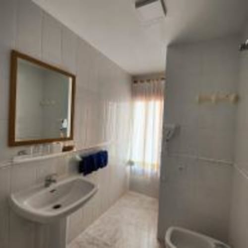 Baño luminoso en Hostal las Dunas de Cabo de Gata con lavabo, espejo, ducha y ventana con luz natural