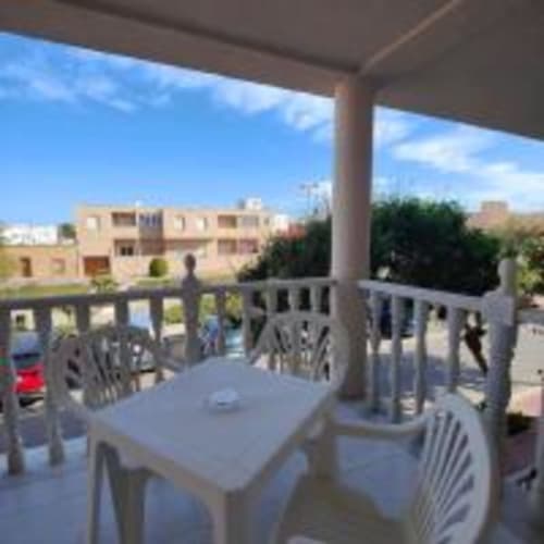 Terraza del Hostal las Dunas en Cabo de Gata con mesas, sillas y vista costera de edificios blanqueados