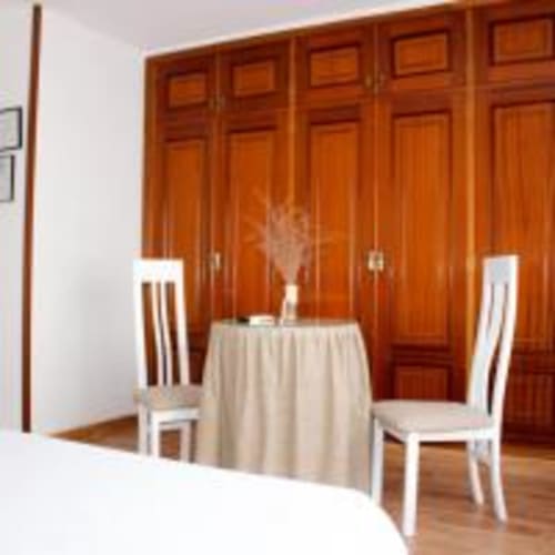 Habitación Triple Superior en Hostal las Dunas de Cabo de Gata con armario de madera, mesa redonda y sillas blancas