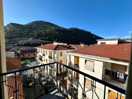 Vista dal balcone dell'appartamento Welcome Holiday a Finale Ligure con tetti in terracotta, collina e cielo azzurro limpido