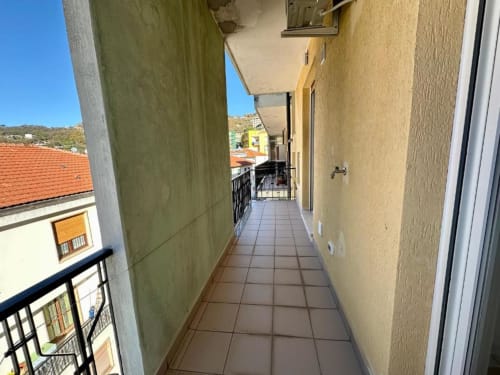 Stretto corridoio con balcone presso Welcome Holiday a Finale Ligure, pavimento piastrellato e vista sulle montagne