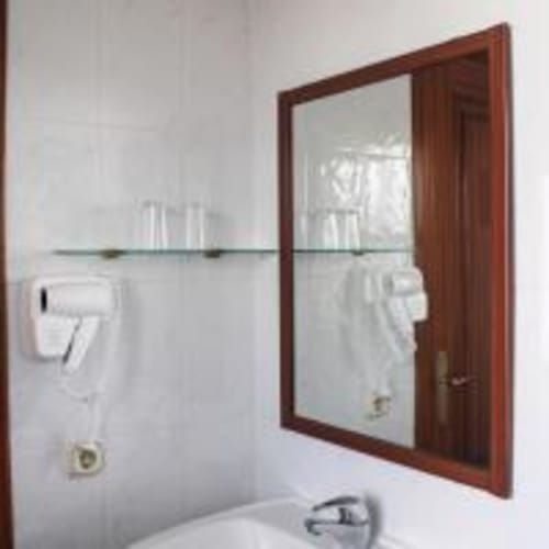 Baño moderno del Hostal las Dunas en Cabo de Gata con espejo de marco de madera, repisa de cristal y paredes alicatadas en blanco