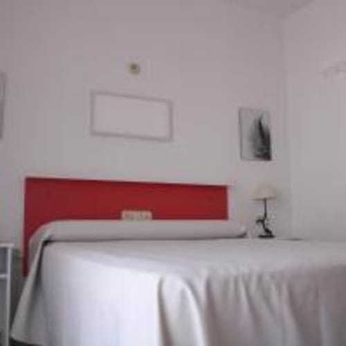 Habitación moderna del Hostal las Dunas en Cabo de Gata con cabecero rojo, ropa de cama blanca y decoración minimalista