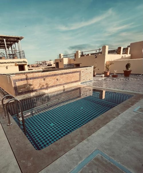 Piscine sur la terrasse du Riad Dar Tahri à Fès avec bassin en zellige turquoise, architecture traditionnelle et jardinières en terre cuite