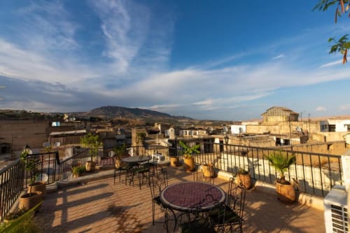 Terrasse panoramique du Riad Dar Tahri à Fès avec vue sur les montagnes, espace repas et architecture traditionnelle marocaine
