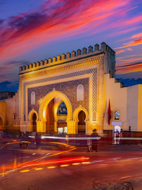 Entrée de l'hôtel Riad Dar Tahri à Fès illuminée au coucher du soleil, avec ses arches ornées et son architecture marocaine traditionnelle