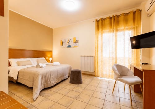 Luminosa camera matrimoniale doppia a La Zagara Rooms a Milazzo con vista sulla città, TV a schermo piatto e arredamento moderno