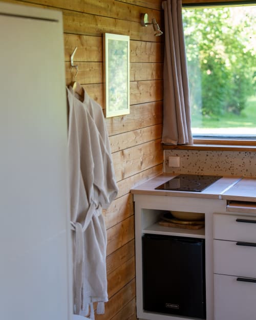 Petite cuisine aux murs en bois, lave-vaisselle compact et vue sur la fenêtre aux cabanes de Julie, Lissac et Mouret