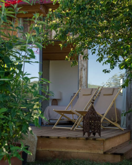 Terrasse cosy avec transats en bois à Les cabanes de Julie, hôtel dans les arbres à Lissac, France