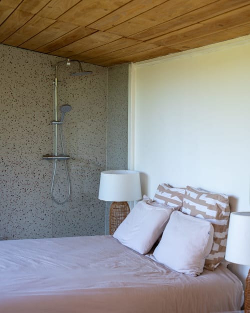Chambre douillette aux poutres en bois, lit garni de coussins et douche moderne aux Cabanes de Julie