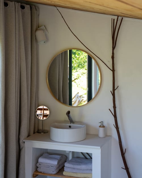 Lavabo blanc moderne avec miroir rond doré aux Cabanes de Julie à Lissac-et-Mouret