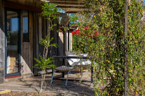Terrasse de jardin luxuriante aux Cabanes de Julie avec mobilier moderne, vignes grimpantes et fleurs rouges à Lissac et Mouret
