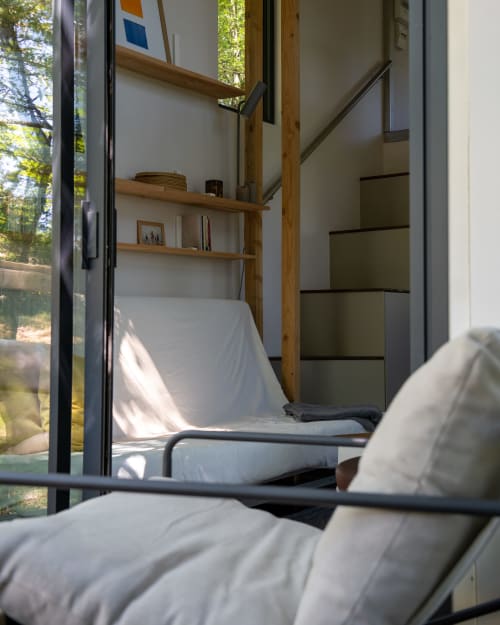 Chambre dans les arbres contemporaine aux Cabanes de Julie : poutres en bois, draps blancs, vue sur la forêt par grandes fenêtres