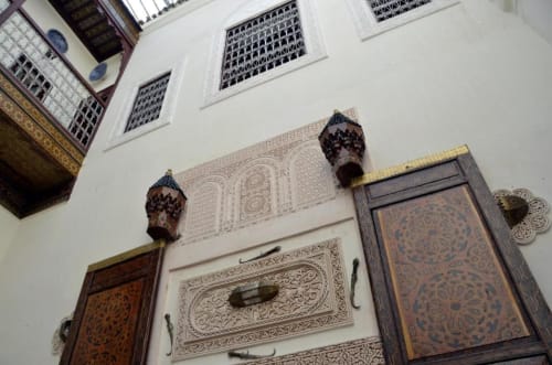 Portique marocain orné de détails en plâtre ciselé, portes en bois sculptées et lanternes dans la cour du Riad Dar Tahri, Fès