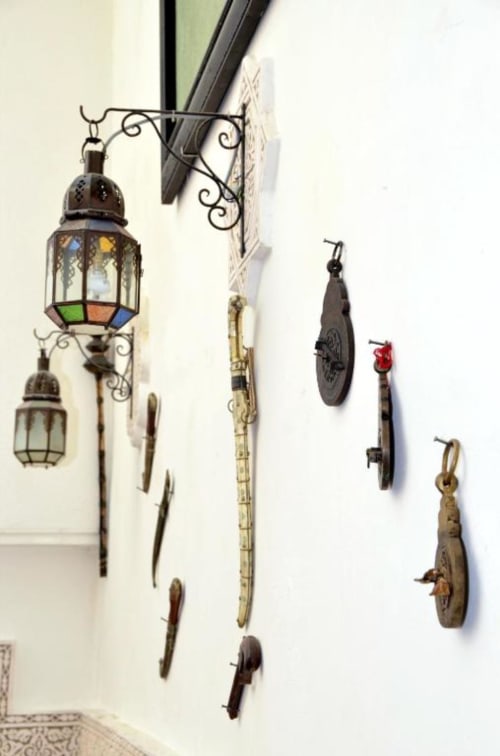 Lanternes décoratives suspendues et ornements métalliques sur mur blanc au Riad Dar Tahri, Fès Maroc