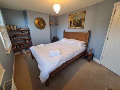 Spacious bedroom at 2 Doves Holiday Property in Exeter with wooden bed, white linens, bookshelves, and classic décor.