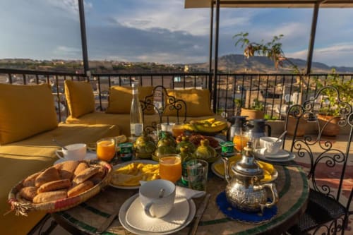 Petit-déjeuner sur la terrasse du Riad Dar Tahri à Fès avec viennoiseries, jus frais et vue sur les montagnes