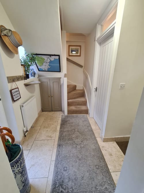 Bright hallway at 2 Doves Holiday Property in Exeter with tiled flooring, stairs, and white doors leading to various rooms