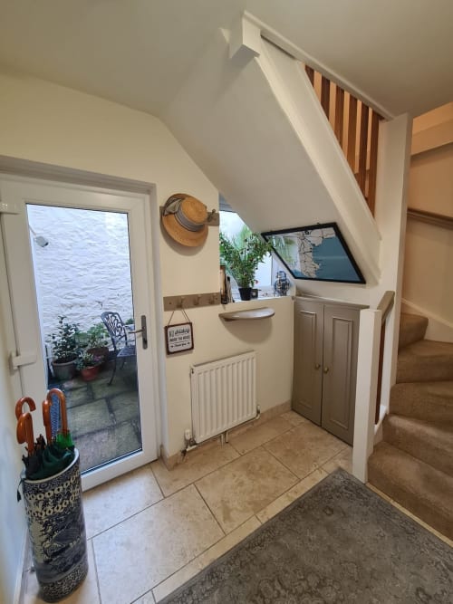 Bright entrance hallway at 2 Doves Holiday Property in Exeter with door to patio, radiator, storage, and staircase