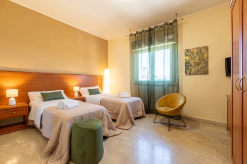 Spaziosa camera familiare a La Zagara a Milazzo con letti gemelli, vista città, arredamento moderno e finestre con vista mare
