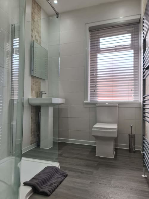Modern bathroom at 2 Doves Holiday Property, Exeter with walk-in shower, pedestal sink, toilet and heated towel rail
