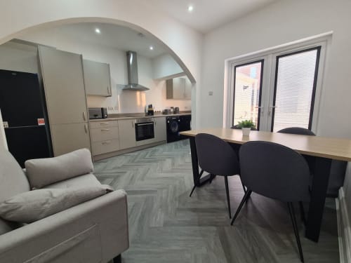 Modern open-plan kitchen and dining area at 2 Doves Holiday Property in Exeter with beige cabinetry, breakfast bar, and
