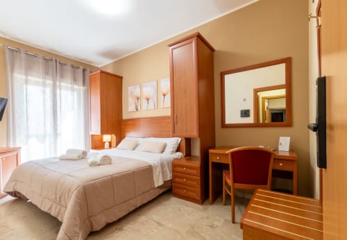 Spaziosissima camera familiare a La Zagara Rooms a Milazzo con arredi in legno, accesso al balcone e vista sulla città