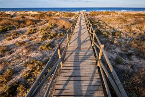 Pasarela de madera extendiéndose hacia el mar azul a través de las dunas costeras cerca de Ròtova, España