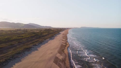 Vista aérea de la playa de arena pristina con olas cerca de Ròtova, España, con paisaje costero y montañas