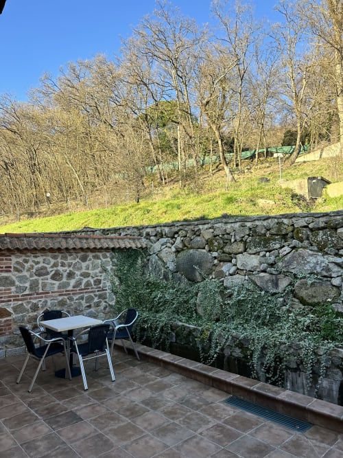 Patio exterior con mesa y sillas en El Escondite De Pedro Malillo en Candeleda, con vistas a la ladera boscosa