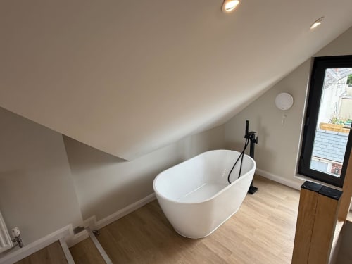 Modern white freestanding bathtub in bright attic bedroom at 2 Doves Holiday Property, Exeter