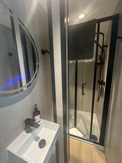 Modern bathroom at 2 Doves Holiday Property in Exeter with glass shower enclosure and illuminated mirror