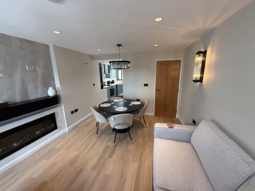 Modern open-plan living area at 2 Doves Holiday Property in Exeter with dining table, sofa, fireplace, and kitchen.