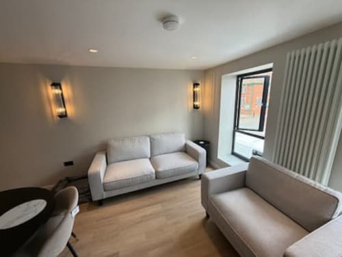 Modern living room at 2 Doves Holiday Property in Exeter with light grey sofas, wooden flooring, and contemporary wall