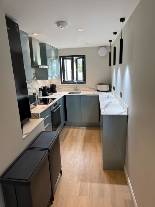 Modern kitchen at 2 Doves Holiday Property in Exeter with dark cabinetry, marble countertops, and stainless steel appliances
