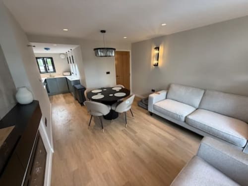 Modern open-plan living area at 2 Doves Holiday Property, Exeter with grey sofa, black dining table, and kitchen