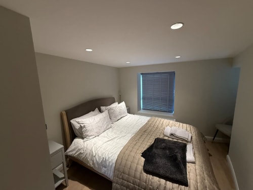 Modern bedroom at 2 Doves Holiday Property in Exeter with queen bed, recessed lighting, and blue shuttered window