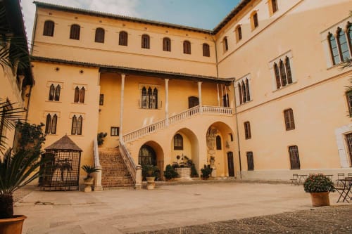 Patio de La Caseta de Ròtova con muros de terracota, arcos, macetas y arquitectura mediterránea en Ròtova, España.