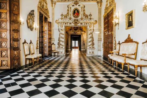 Salón palaciego ornamentado con piso de cuadros blanco y negro, puertas doradas y mobiliario de época en La Caseta de Ròtova