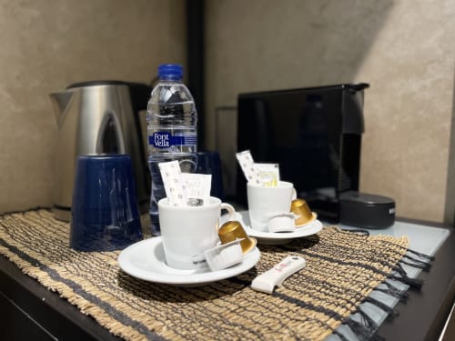 Amenidades de bienvenida en habitación del Mamma Mia Tossa: servicio de café con cápsulas Nespresso, botella de agua y artículos de aseo