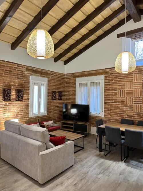 Sala de estar rústica moderna en El Escondite De Pedro Malillo en Candeleda con ladrillo expuesto, vigas de madera y diseño contemporáneo