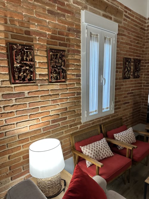 Acogedora habitación de ladrillo en El Escondite De Pedro Malillo con sillones rojos, arte decorativo y ventana moderna en Candeleda