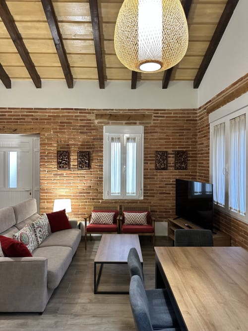 Moderna sala de estar en El Escondite De Pedro Malillo en Candeleda con ladrillo visto, iluminación colgante y cómoda zona de estar