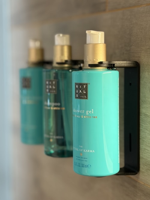 Colección de artículos de tocador de lujo en Hotel Boutique Mamma Mia Tossa, con gel de ducha turquesa y amenidades premium